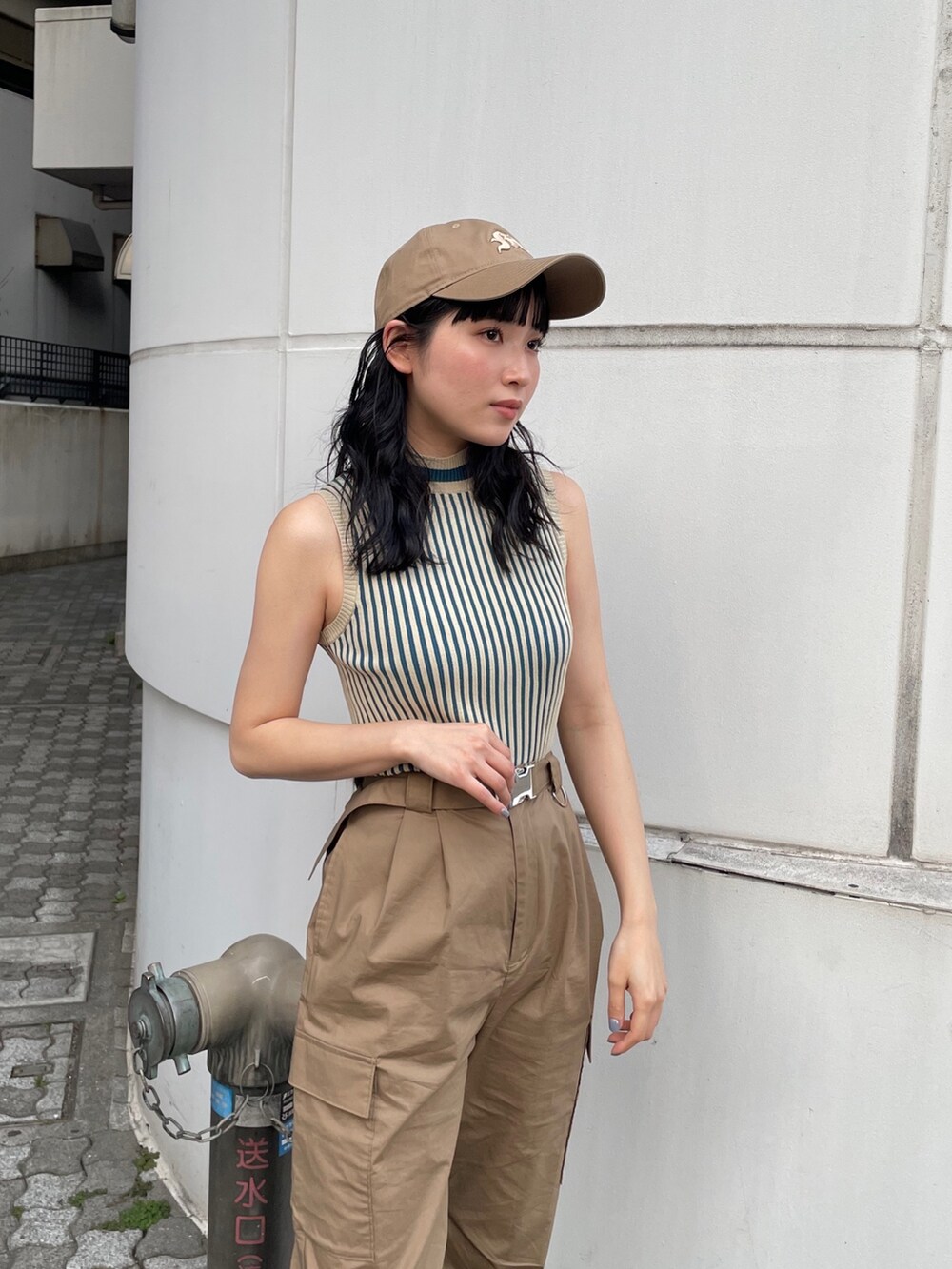 グリーン系のカーゴパンツ、ベージュ系のニット/セーター、ベージュ系のキャップを着用したレディースの春コーディネートの3枚目の写真