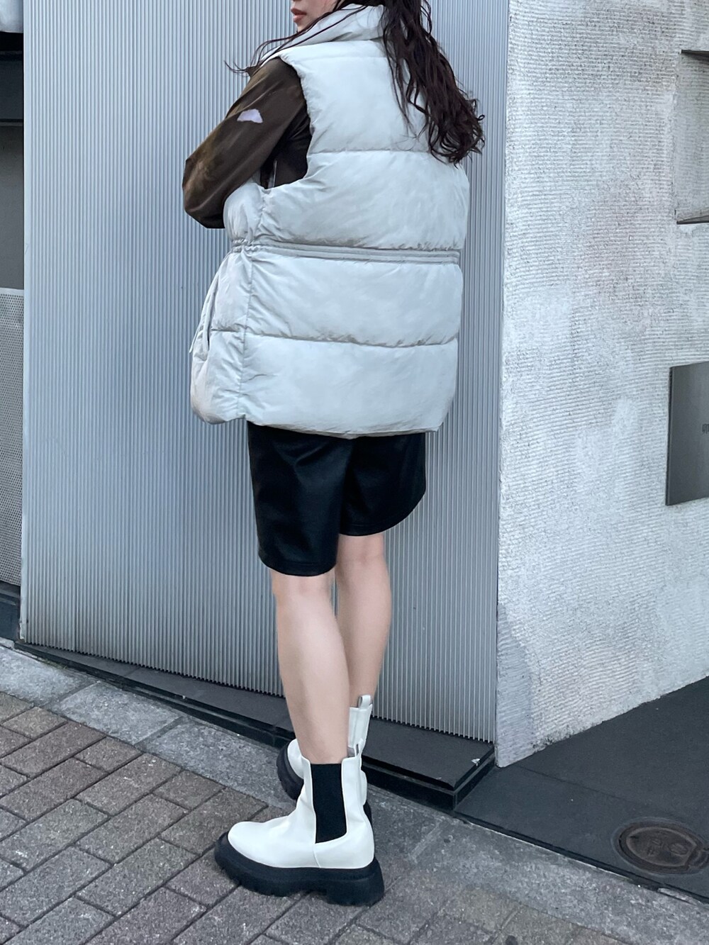 ホワイト系のTシャツ/カットソー、グレー系のダウンベスト、ブラック系のその他パンツを着用したレディースの秋コーディネートの3枚目の写真