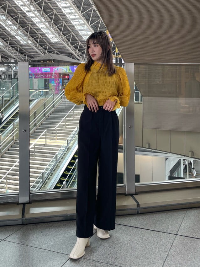 イエロー系のシャツ/ブラウス、ホワイト系のブーツ、ブラック系のスラックスを着用したレディースの夏コーディネートの2枚目の写真