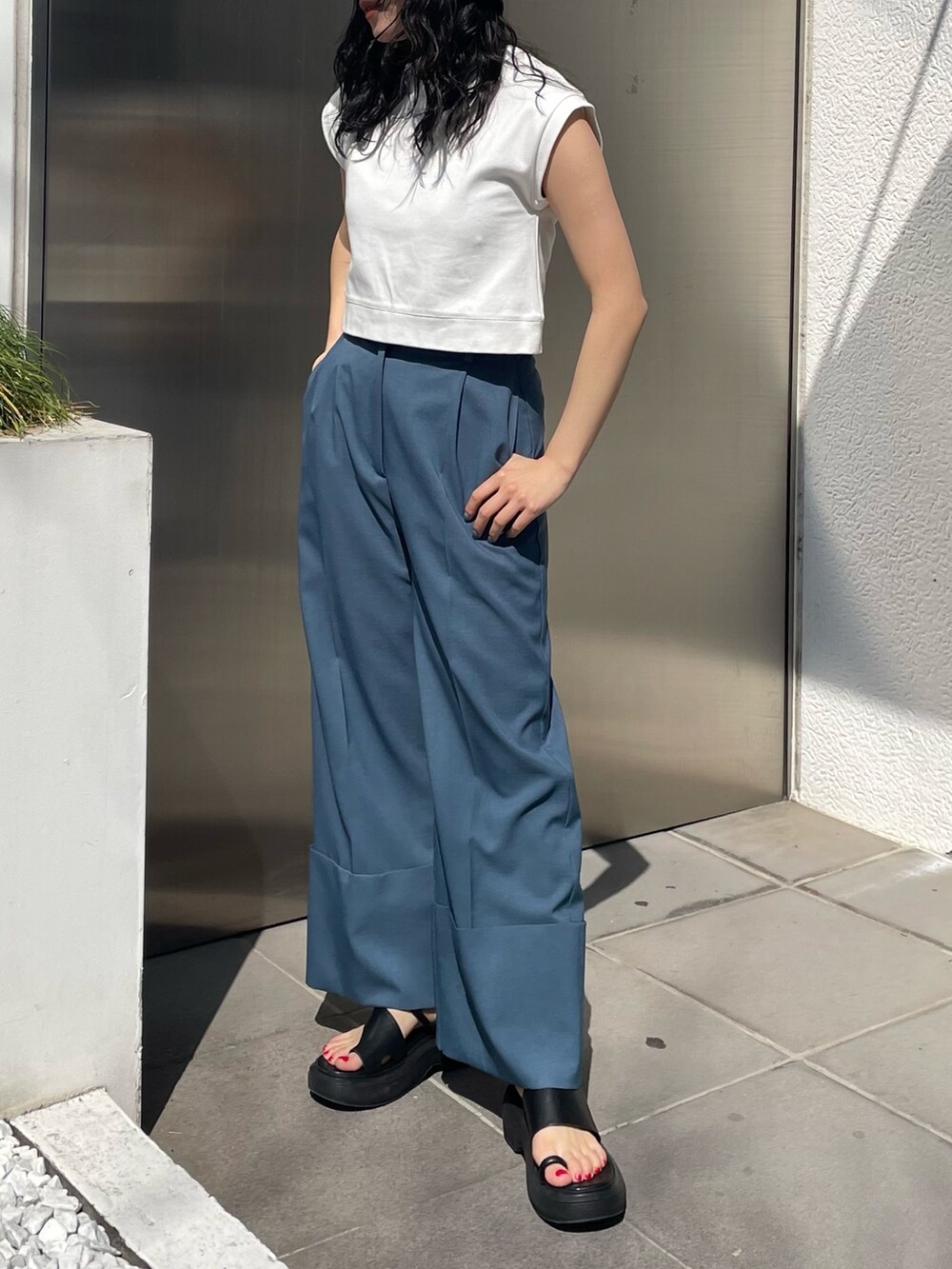 ブラック系のサンダル、ブルー系のスラックス、ホワイト系のタンクトップを着用したレディースの春コーディネートの2枚目の写真