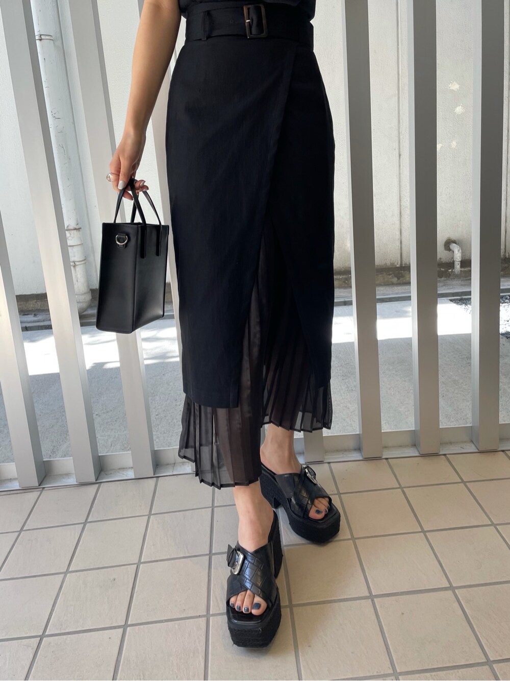 ブラック系のスカート、ブラック系のサンダル、ブラック系のニット/セーターを着用したレディースの春コーディネートの6枚目の写真