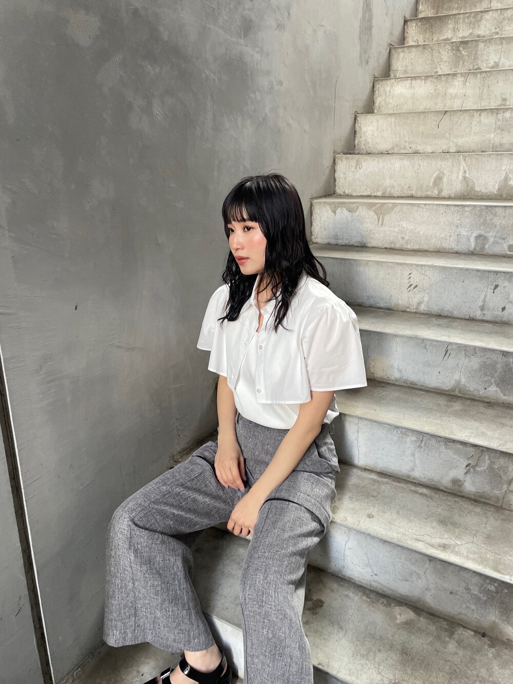 ホワイト系のシャツ/ブラウス、グレー系のスラックス、ブラック系のサンダルを着用したレディースの春コーディネートの3枚目の写真