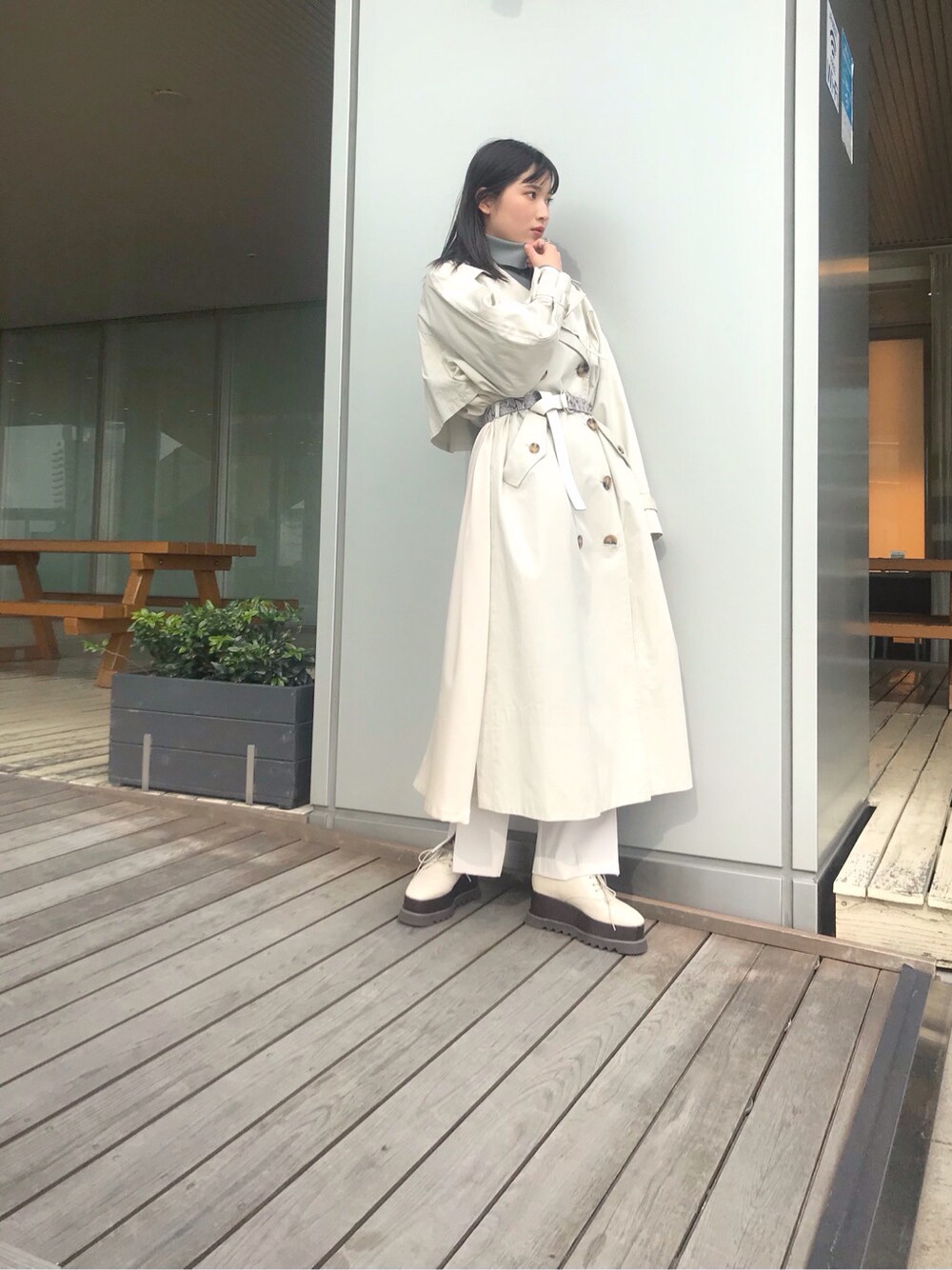 グリーン系のニット/セーター、ホワイト系のトレンチコート、ホワイト系のローファーを着用したレディースの冬コーディネートの2枚目の写真