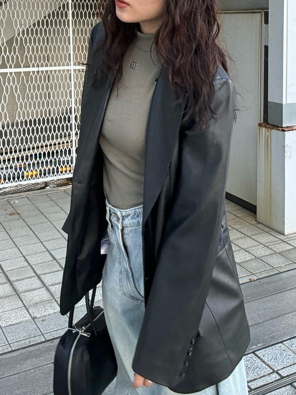 ブラック系のテーラードジャケット、グリーン系のTシャツ/カットソー、ブルー系のデニムパンツを着用したレディースの夏コーディネートの2枚目の写真