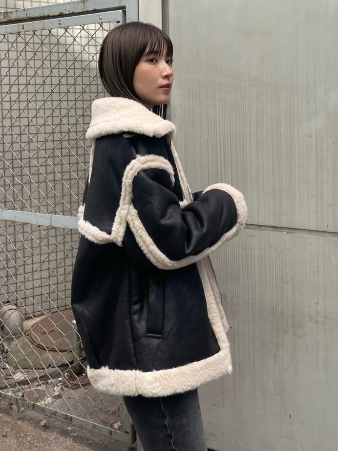 ブラック系のブーツ、ブルー系のニット/セーター、ブラック系のムートンコートを着用したレディースの秋コーディネートの5枚目の写真