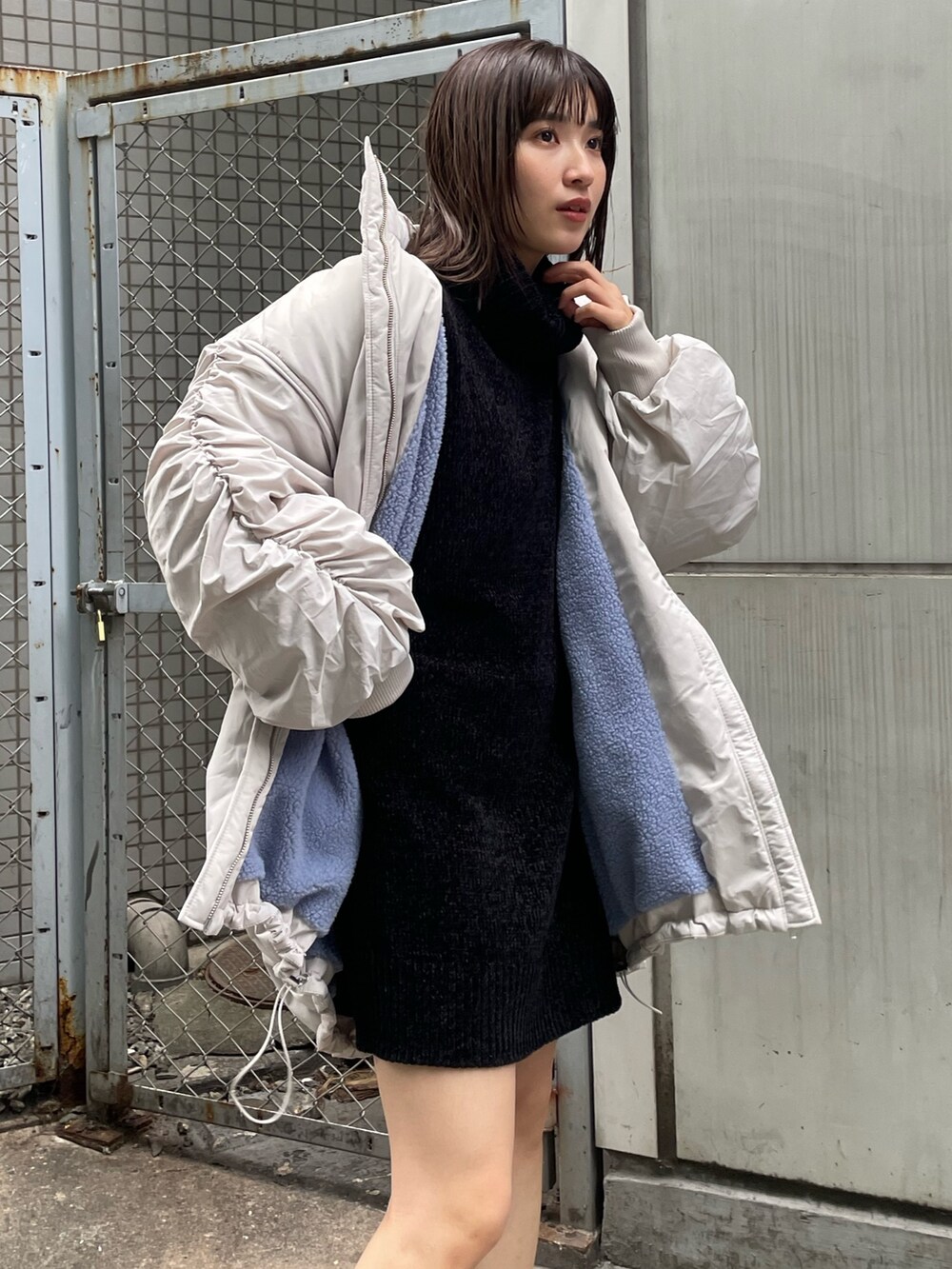 ホワイト系のブルゾン、ブラック系のワンピース、ブラック系のブーツを着用したレディースの冬コーディネートの4枚目の写真