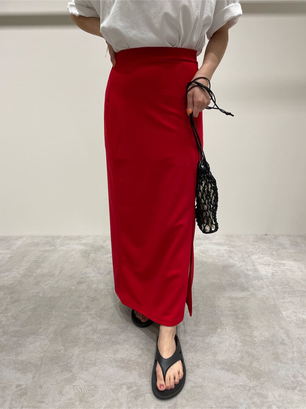 ブラック系のハンドバッグ、ホワイト系のTシャツ/カットソー、レッド系のスカートを着用したレディースの夏コーディネートの7枚目の写真