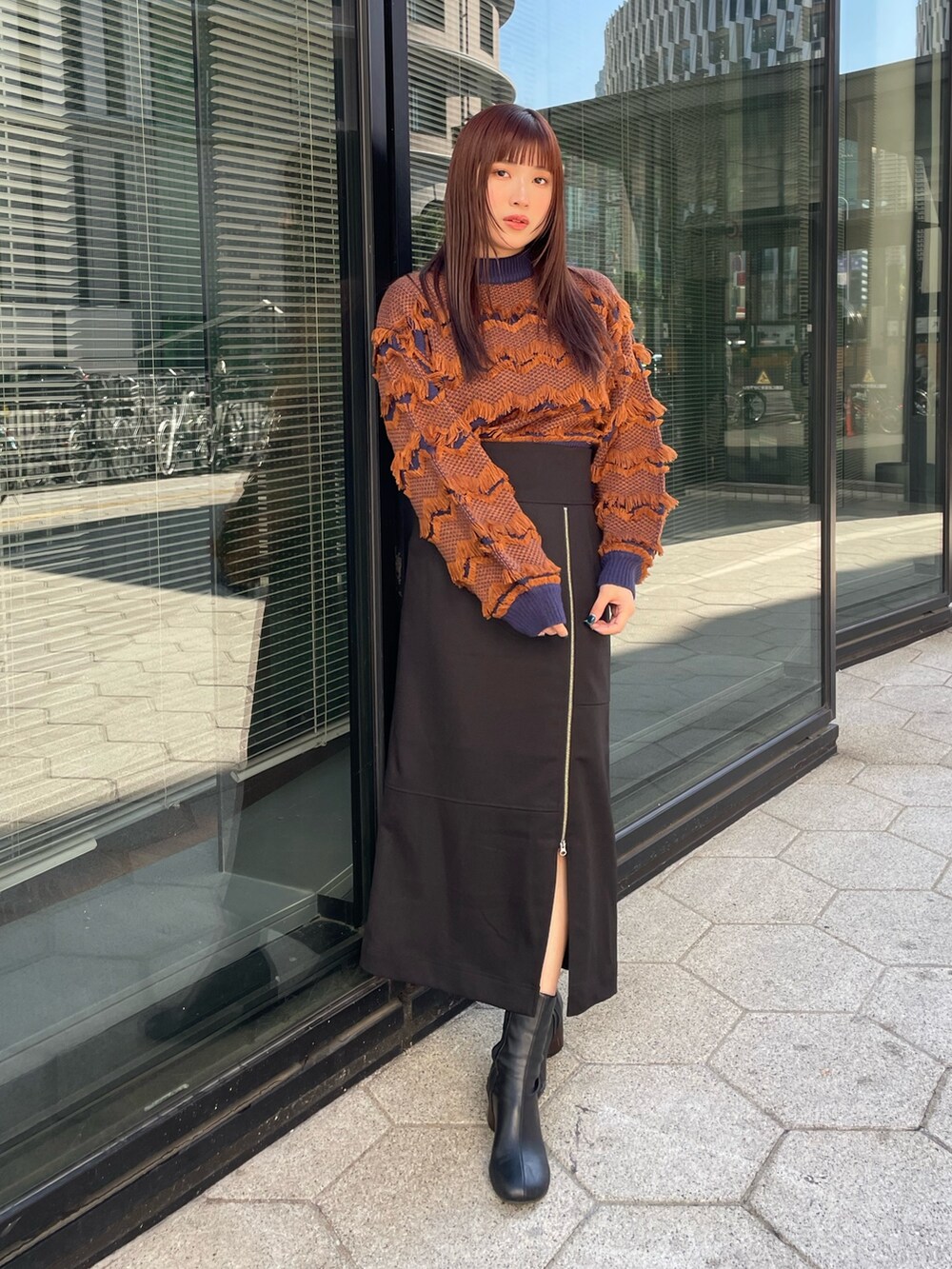 ブラック系のスカート、オレンジ系のニット/セーターを着用したレディースの秋コーディネートの2枚目の写真