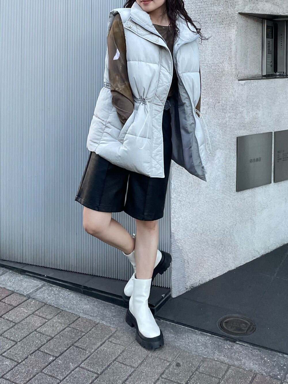 ホワイト系のTシャツ/カットソー、グレー系のダウンベスト、ブラック系のその他パンツを着用したレディースの秋コーディネートの2枚目の写真