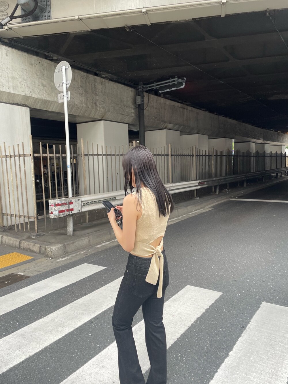 ホワイト系のタンクトップ、ブラック系のデニムパンツ、ブラック系のサンダルを着用したレディースの春コーディネートの4枚目の写真