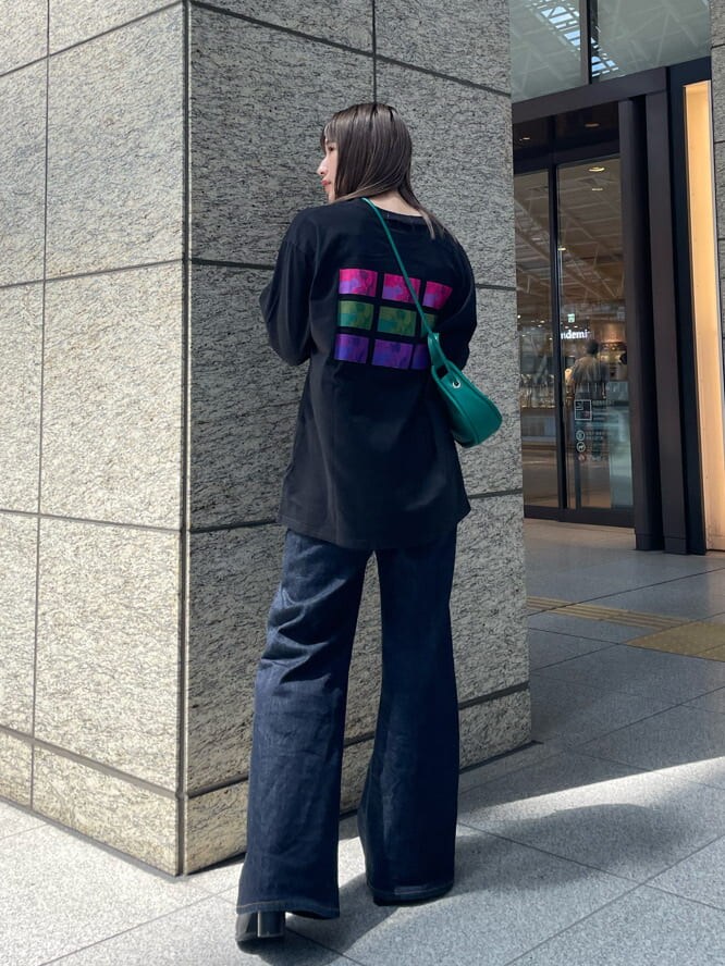 グリーン系のハンドバッグ、ブラック系のブーツ、ブラック系のTシャツ/カットソーを着用したレディースの夏コーディネートの2枚目の写真