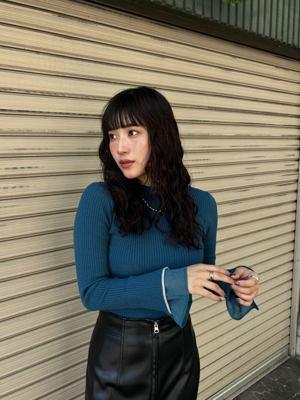 ブルー系のニット/セーター、ブラック系のその他アウター、ブラック系のスカートを着用したレディースの秋コーディネートの6枚目の写真