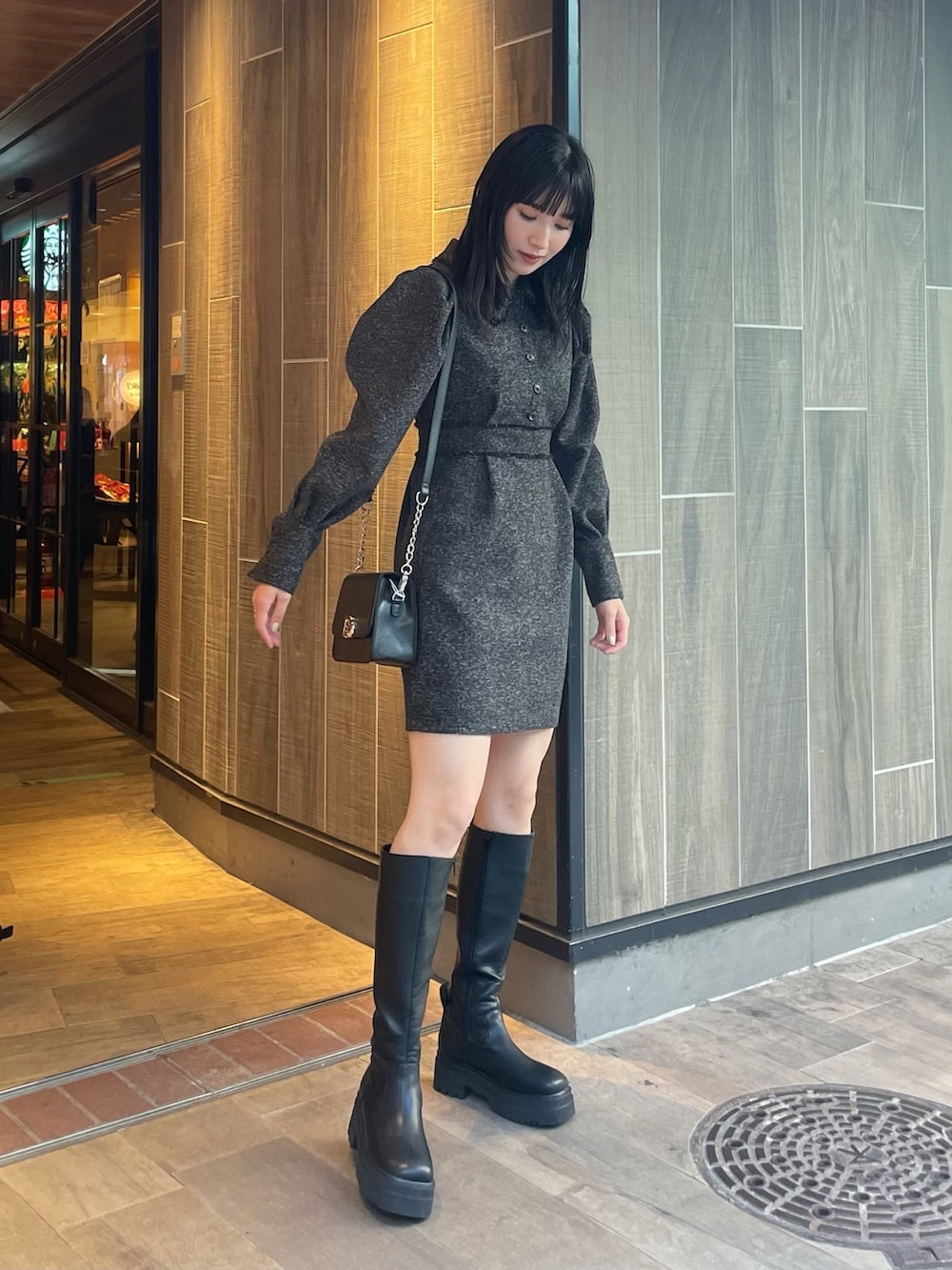 ブラック系のワンピース、ブラック系のブーツ、ブラック系のショルダーバッグを着用したレディースの冬コーディネートの5枚目の写真