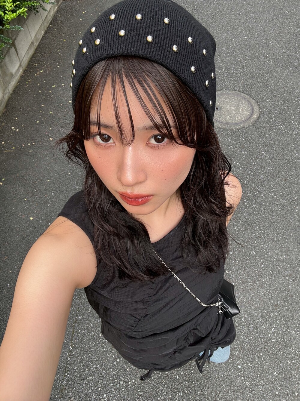 ブラック系のワンピース、ブルー系のデニムパンツ、ブラック系のスニーカーを着用したレディースの春コーディネートの3枚目の写真