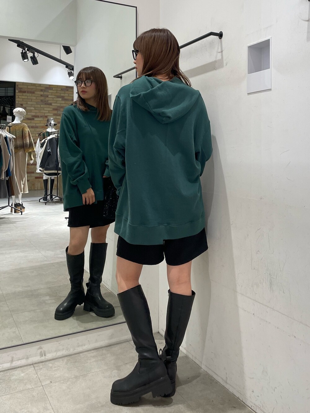 グリーン系のパーカー、ブラック系のブーツを着用したレディースの秋コーディネートの4枚目の写真