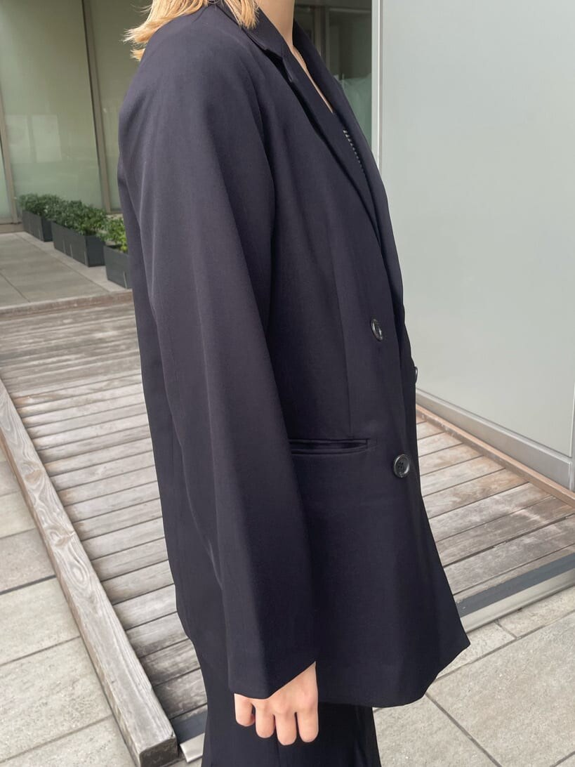 ブラック系のテーラードジャケット、ホワイト系のハンドバッグ、ブラック系のスカートを着用したレディースの春コーディネートの6枚目の写真