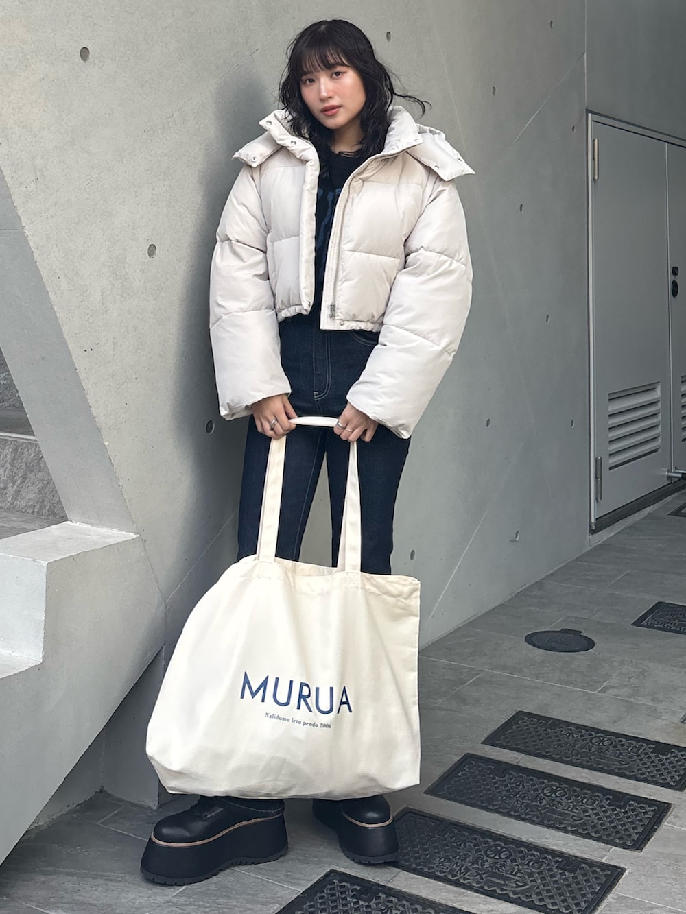 ホワイト系のブルゾン、ブラック系のニット/セーター、ブルー系のデニムパンツを着用したレディースの冬コーディネートの2枚目の写真