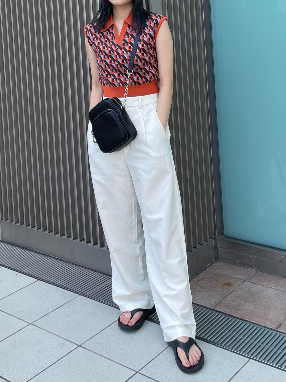 ブラック系のショルダーバッグ、オレンジ系のニット/セーターを着用したレディースの夏コーディネートの3枚目の写真