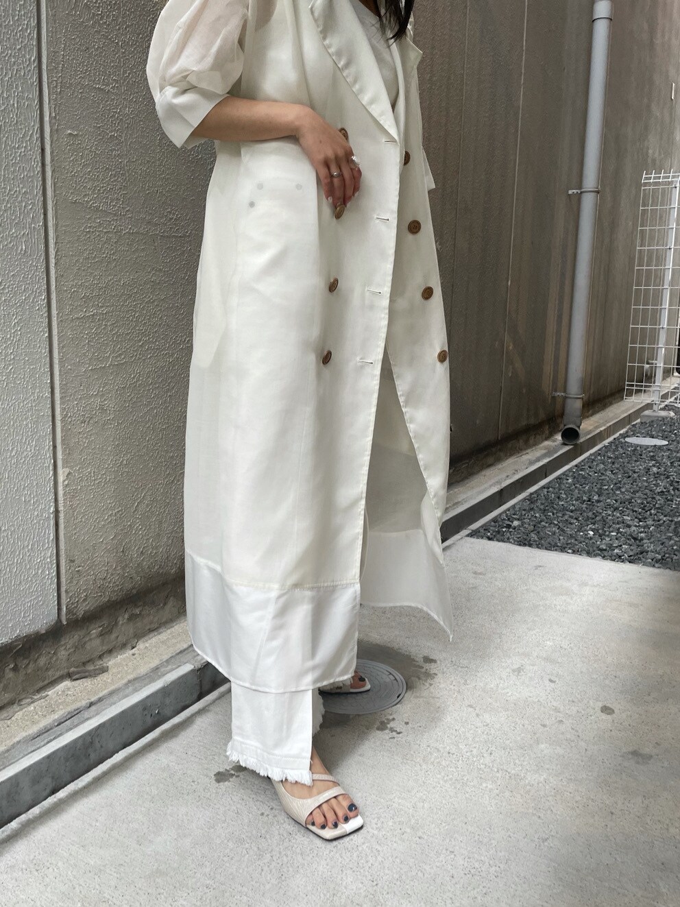 ホワイト系のニット/セーター、ホワイト系のサンダル、ブラウン系のハンドバッグを着用したレディースの春コーディネートの4枚目の写真