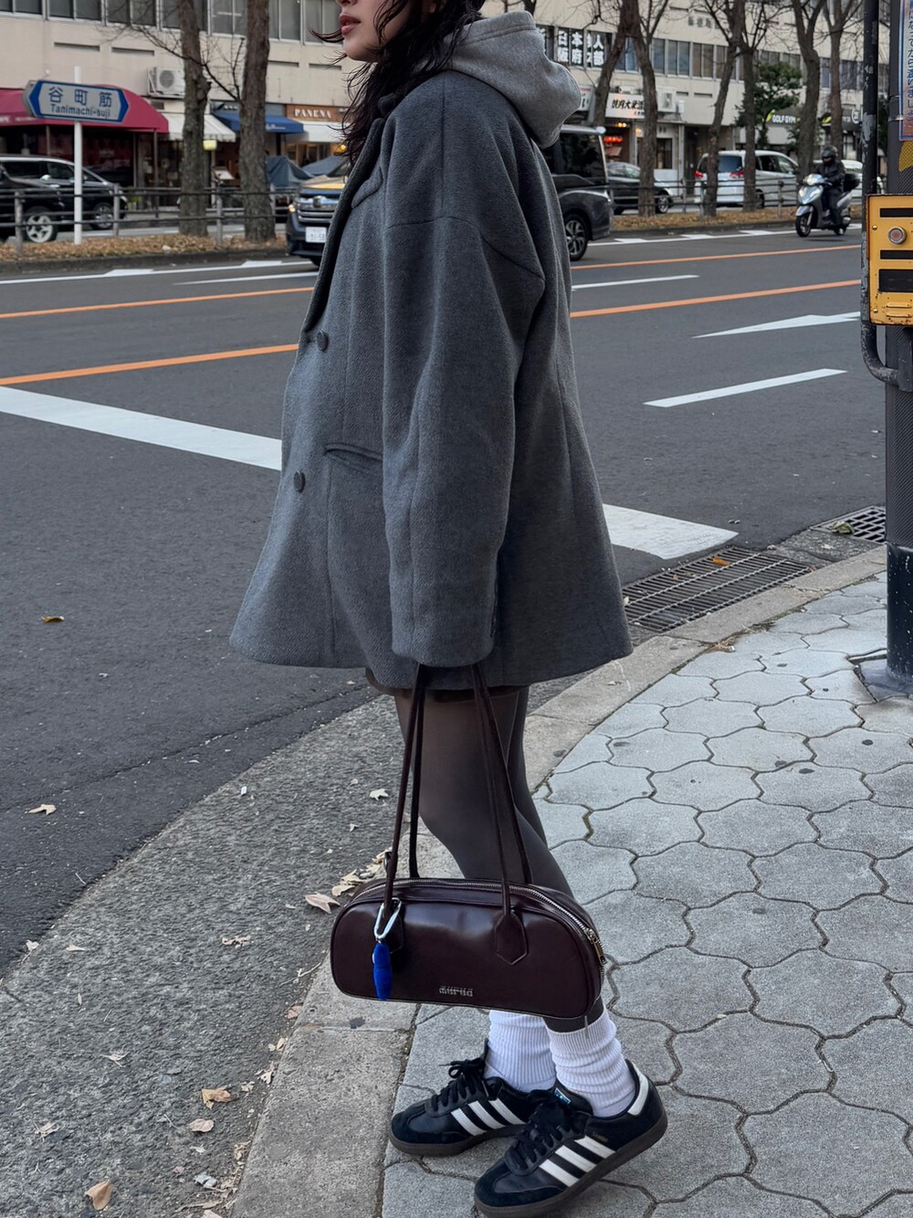 グレー系のテーラードジャケット、ブラウン系のスカート、ブラウン系のボストンバッグを着用したレディースの冬コーディネートの3枚目の写真