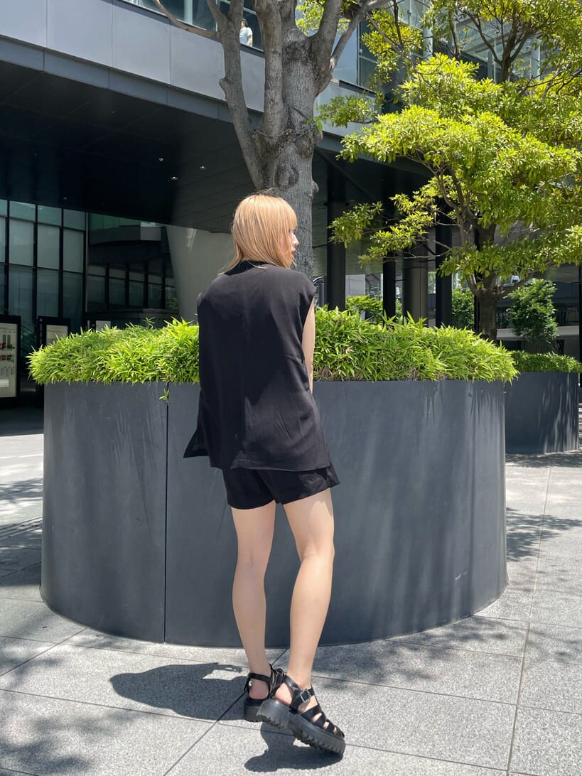 ブラック系のベスト、ブラック系のスラックス、グリーン系のタンクトップを着用したレディースの夏コーディネートの5枚目の写真