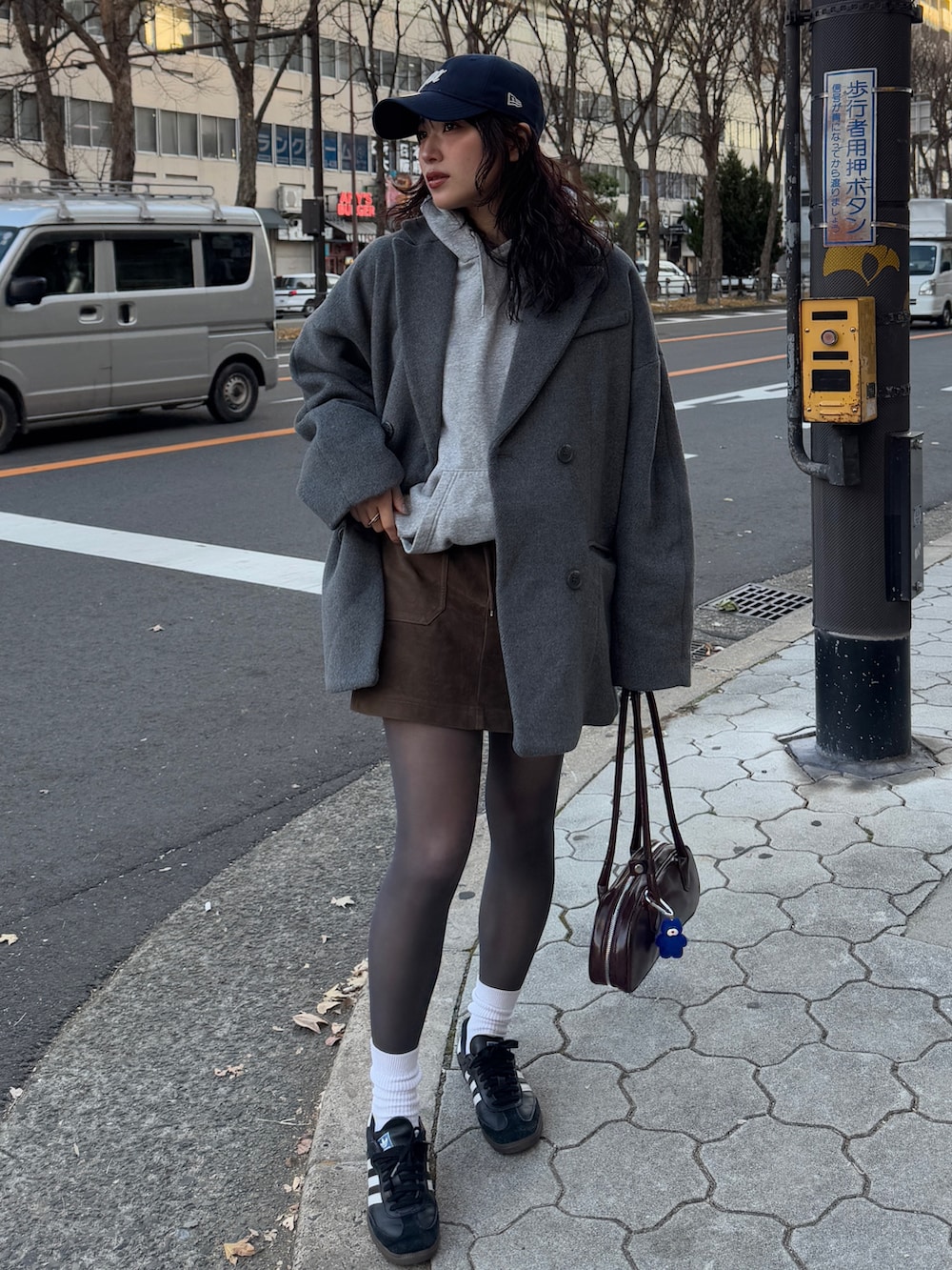グレー系のテーラードジャケット、ブラウン系のスカート、ブラウン系のボストンバッグを着用したレディースの冬コーディネートの2枚目の写真