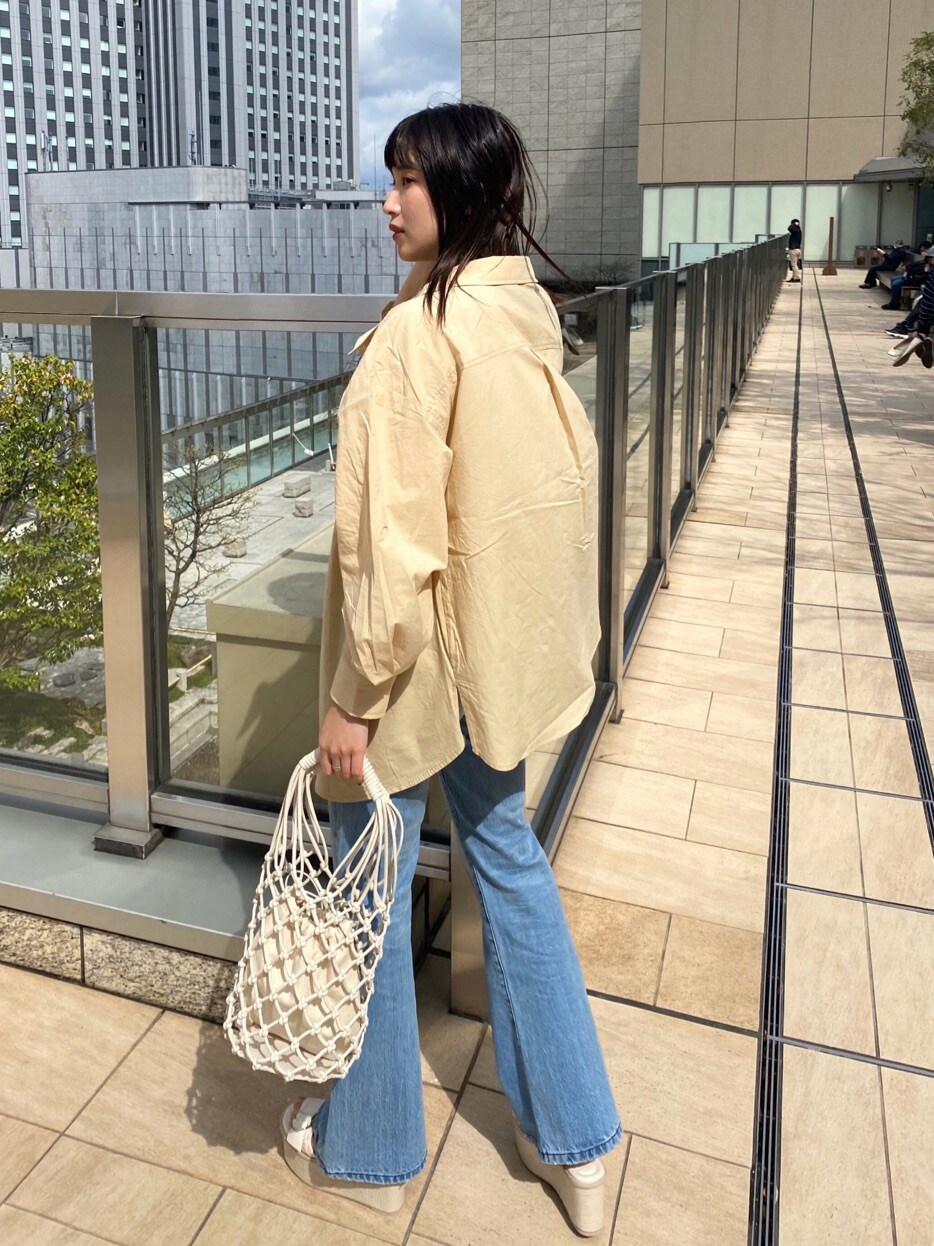 ホワイト系のニット/セーター、イエロー系のシャツ/ブラウス、ホワイト系のハンドバッグを着用したレディースの春コーディネートの5枚目の写真