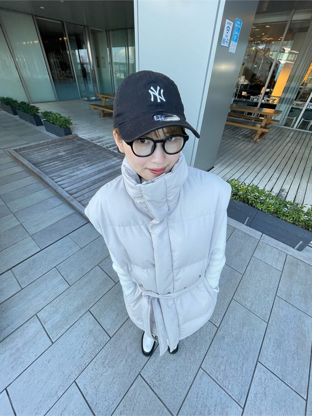 ホワイト系のダウンベスト、ブラック系のデニムパンツ、ホワイト系のニット/セーターを着用したレディースの冬コーディネートの5枚目の写真