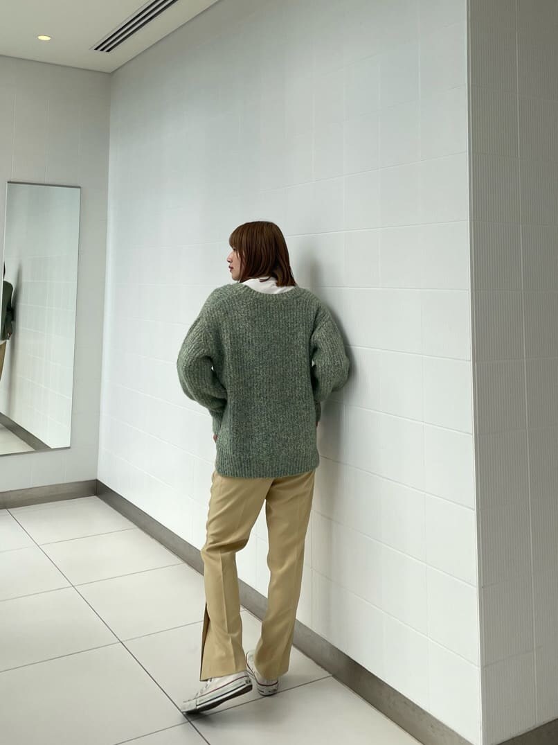 グリーン系のニット/セーター、イエロー系のスラックスを着用したレディースの冬コーディネートの3枚目の写真