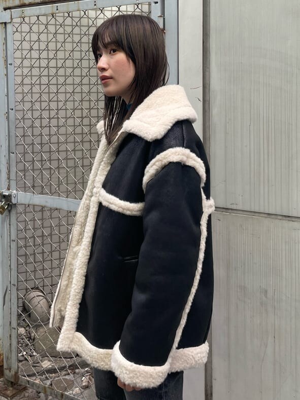 ブラック系のブーツ、ブルー系のニット/セーター、ブラック系のムートンコートを着用したレディースの秋コーディネートの7枚目の写真