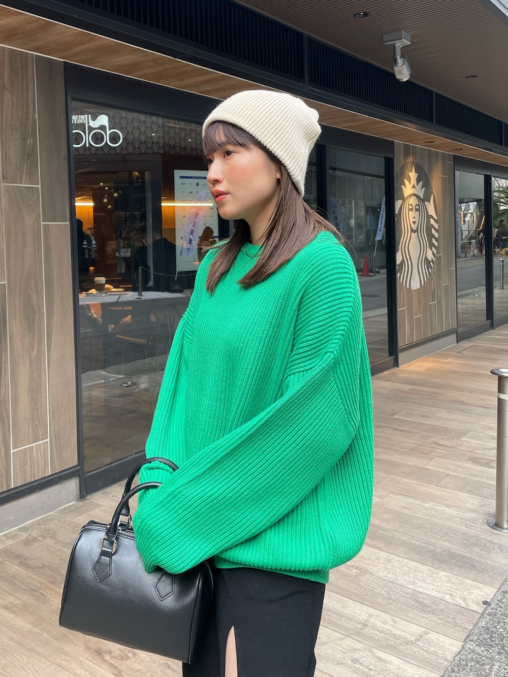 グリーン系のニット/セーター、ブラック系のスカートを着用したレディースの冬コーディネートの7枚目の写真