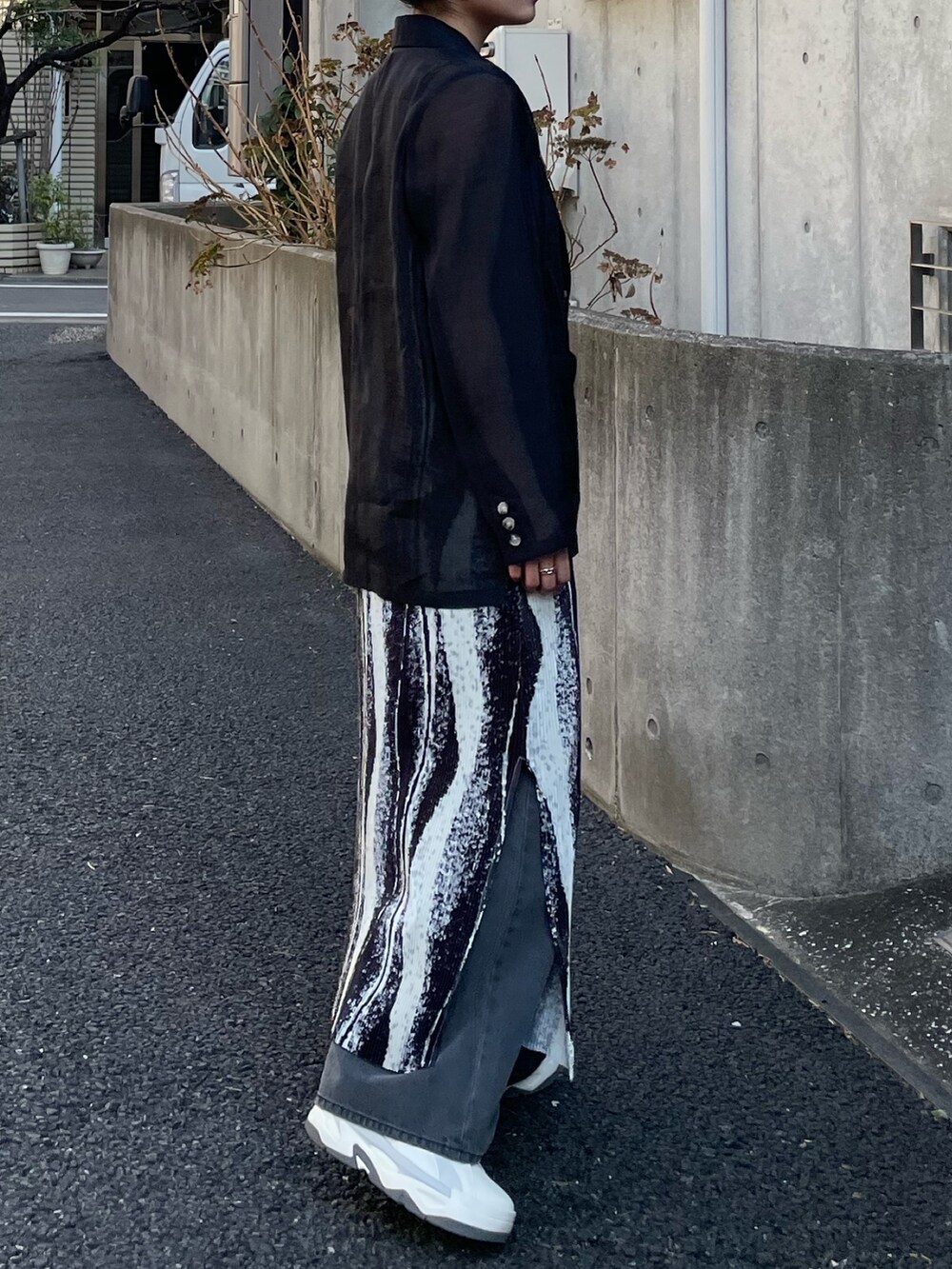 ブラック系のテーラードジャケット、ブラック系のワンピース、ブラック系のデニムパンツを着用したレディースの春コーディネートの2枚目の写真