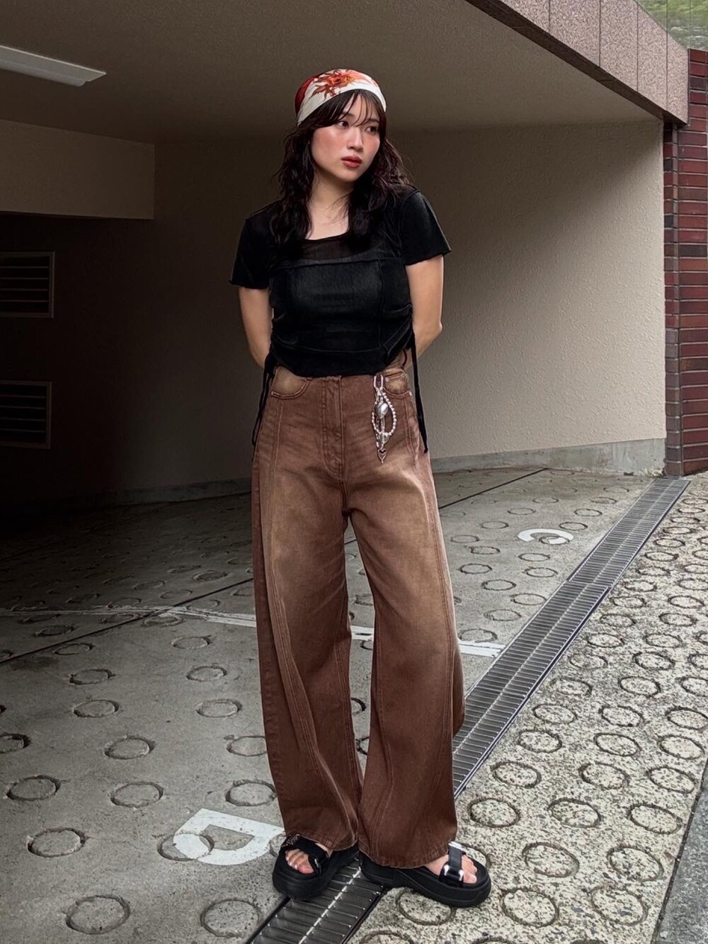 ブラウン系のデニムパンツ、ブラック系のサンダル、オレンジ系のバンダナ/スカーフを着用したレディースの春コーディネートの2枚目の写真