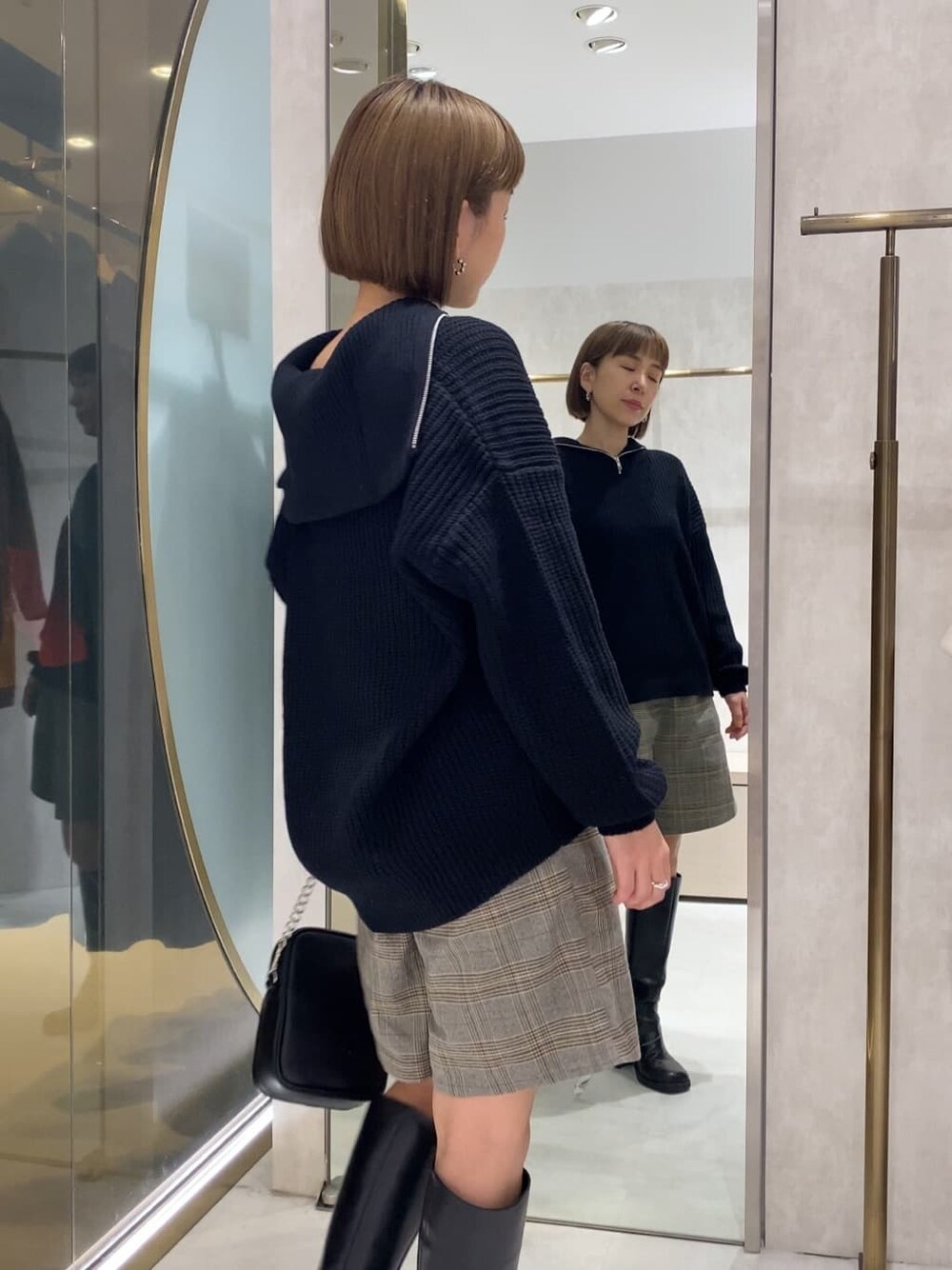 ブラック系のブーツ、ブラック系のニット/セーター、ブラック系のショルダーバッグを着用したレディースの秋コーディネートの2枚目の写真