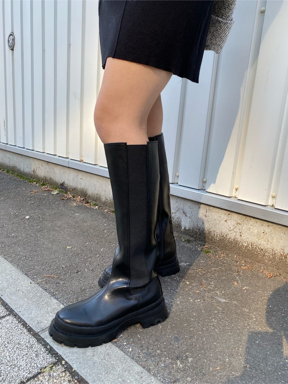 ブラック系のワンピース、ホワイト系のブルゾン、ブラック系のブーツを着用したレディースの秋コーディネートの9枚目の写真