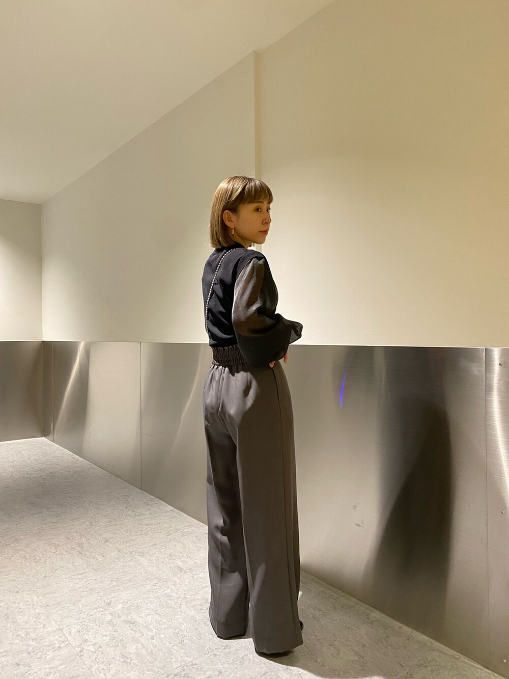 ブラック系のニット/セーター、グレー系のスラックスを着用したレディースの冬コーディネートの4枚目の写真