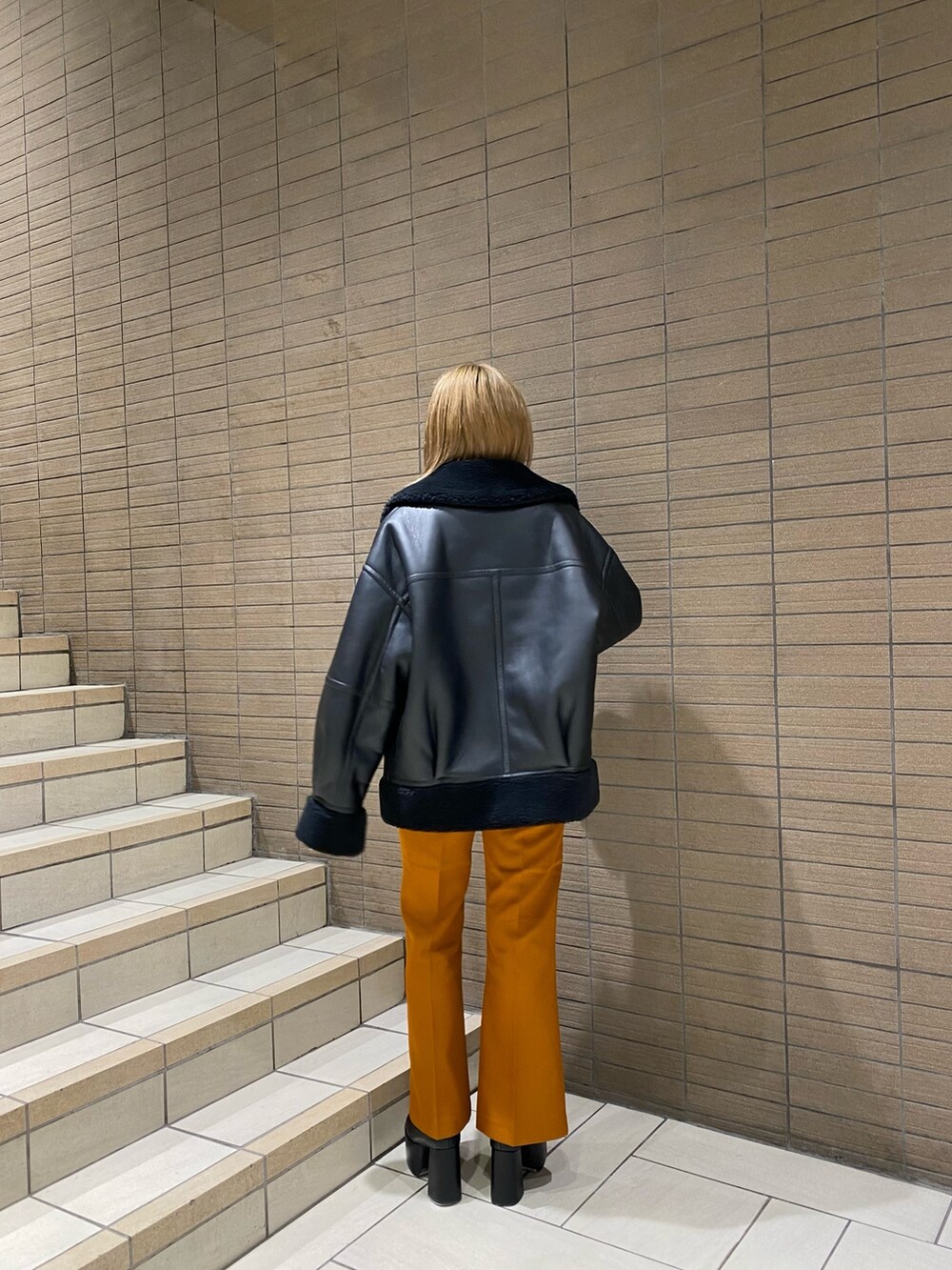 ブラック系のムートンコート、ホワイト系のTシャツ/カットソー、オレンジ系のその他パンツを着用したレディースの夏コーディネートの2枚目の写真
