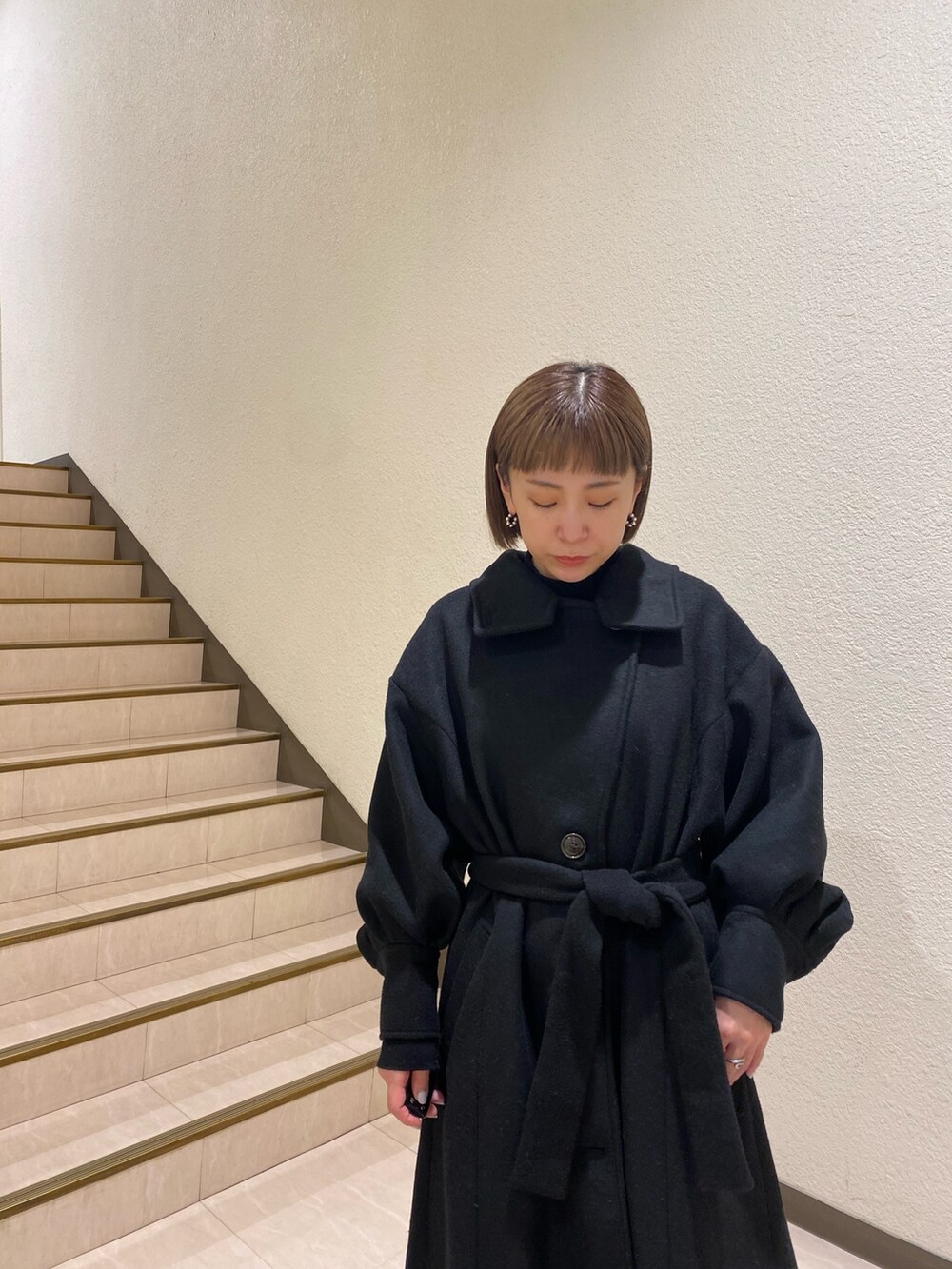 ブラック系のダウンジャケット/コート、パープル系のニット/セーター、グレー系のスラックスを着用したレディースの秋コーディネートの8枚目の写真