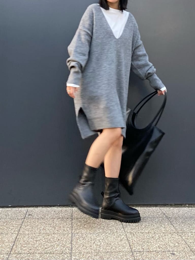 ホワイト系のTシャツ/カットソー、グレー系のニット/セーター、ブラック系のブーツを着用したレディースの秋コーディネートの4枚目の写真