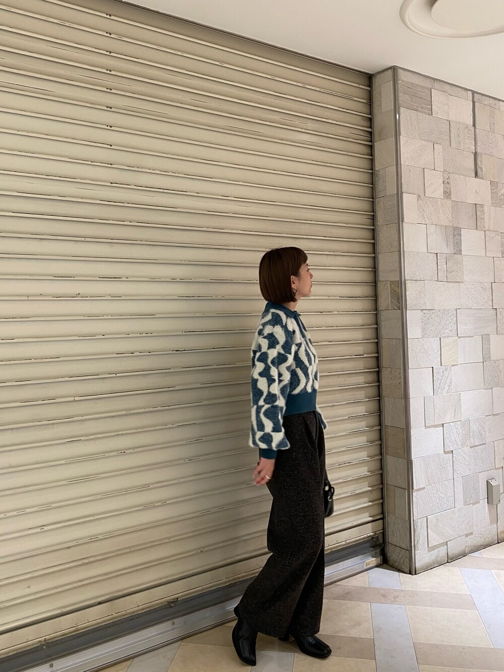 グリーン系のニット/セーター、ブラック系のスラックス、ブラック系のブーツを着用したレディースの秋コーディネートの3枚目の写真