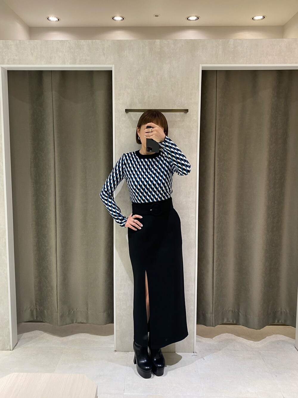 ブラック系のニット/セーター、ブラック系のスカート、ブラック系のブーツを着用したレディースの秋コーディネートの3枚目の写真