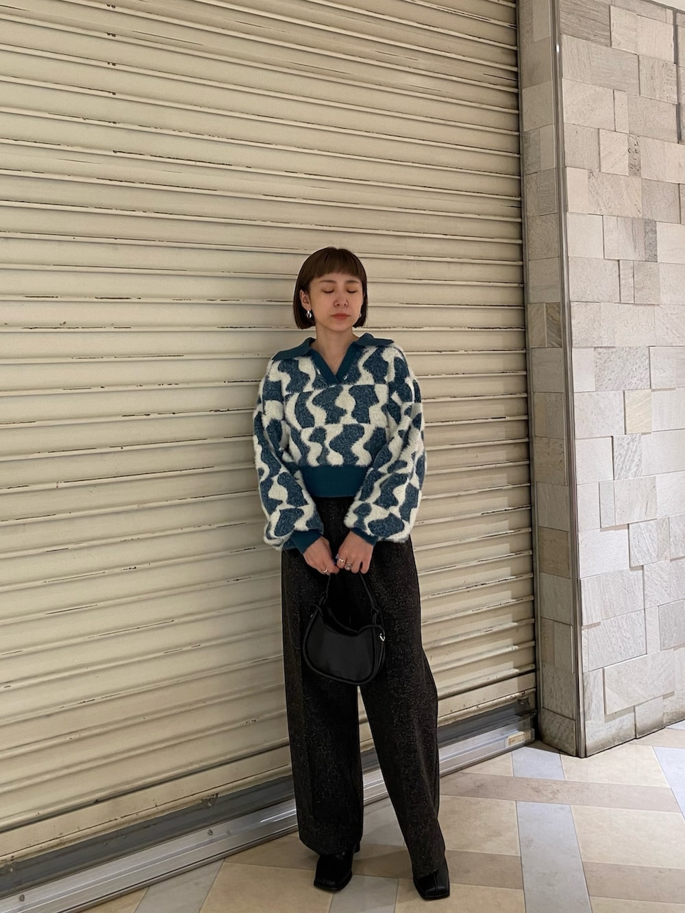 グリーン系のニット/セーター、ブラック系のスラックス、ブラック系のブーツを着用したレディースの秋コーディネートの2枚目の写真