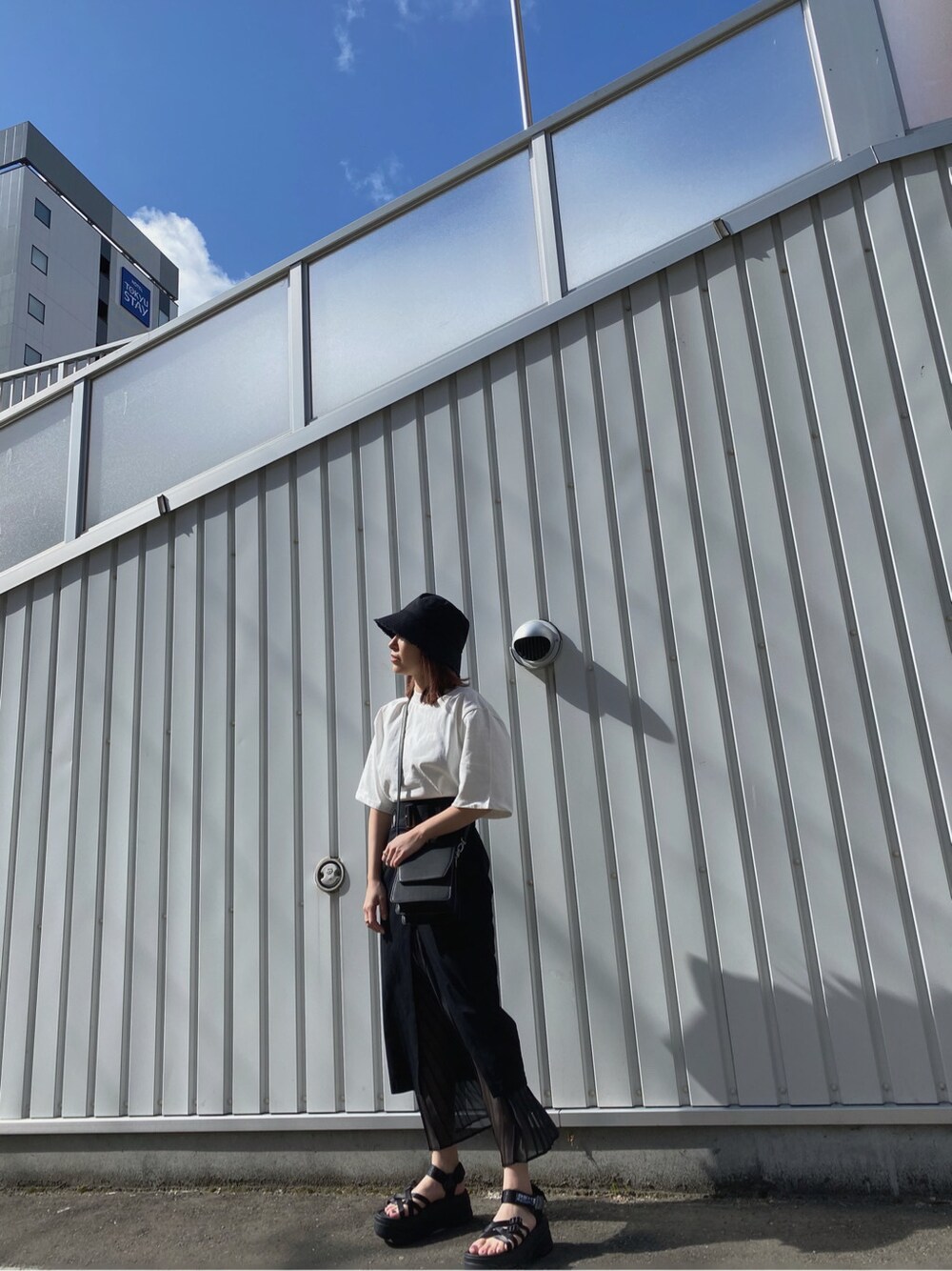 ブラック系のスカート、ホワイト系のTシャツ/カットソー、ブラック系のハンドバッグを着用したレディースの春コーディネートの2枚目の写真