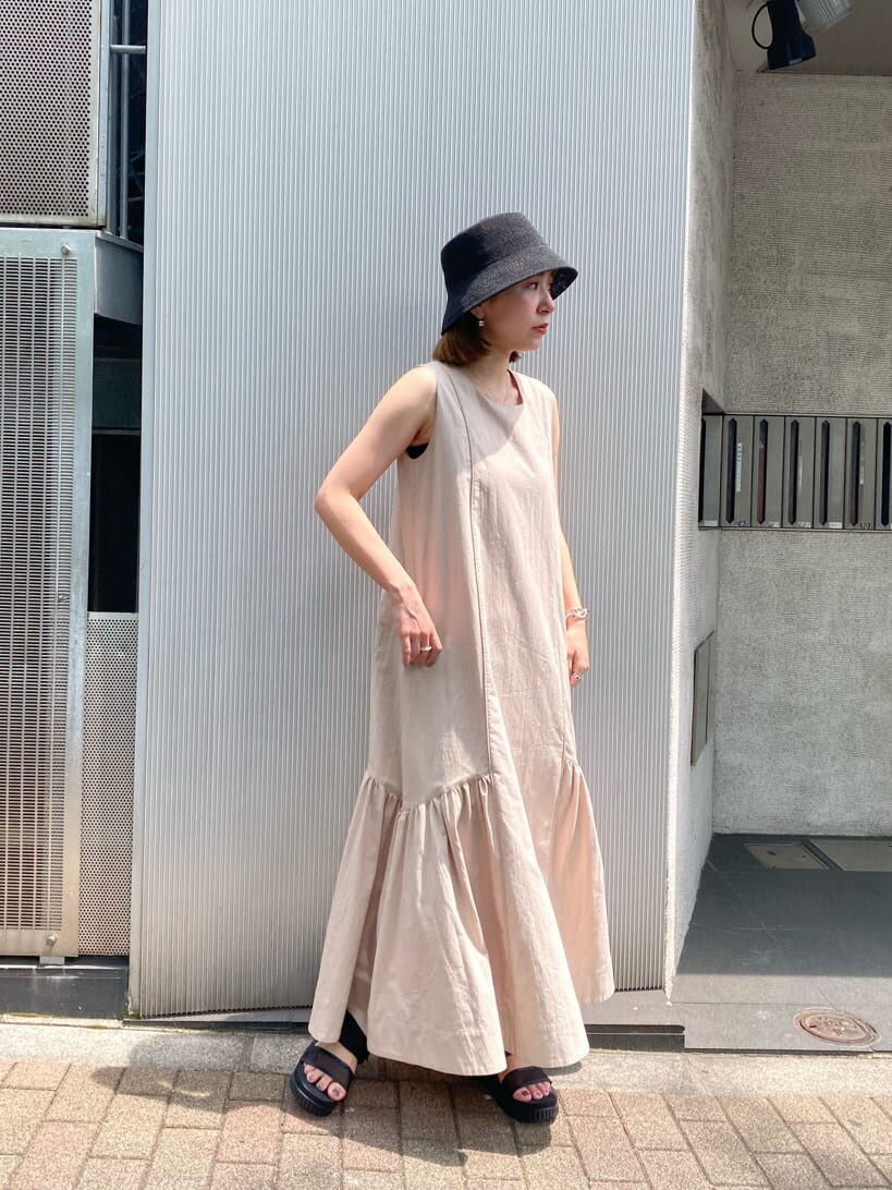 ベージュ系のワンピース、ブラック系のハットを着用したレディースの夏コーディネートの2枚目の写真