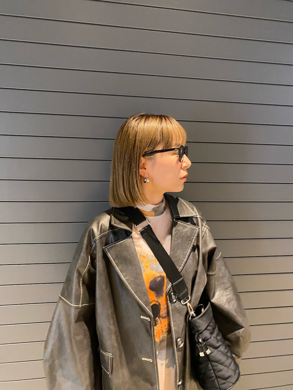 グレー系のブルゾン、オレンジ系のワンピースを着用したレディースの春コーディネートの4枚目の写真