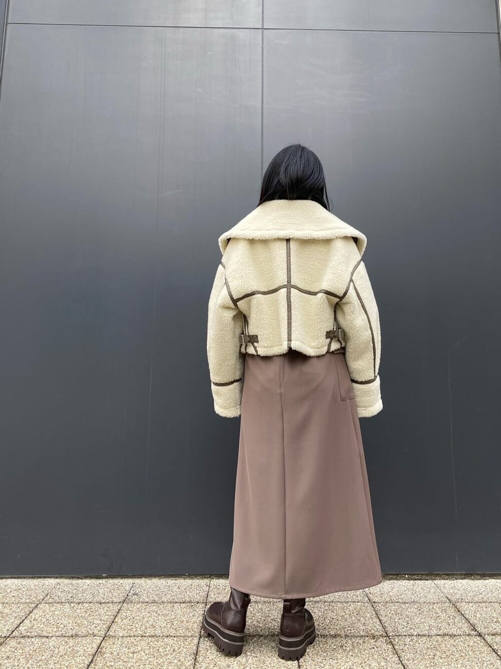 ベージュ系のスカート、ホワイト系のブルゾン、ブラウン系のブーツを着用したレディースの冬コーディネートの2枚目の写真