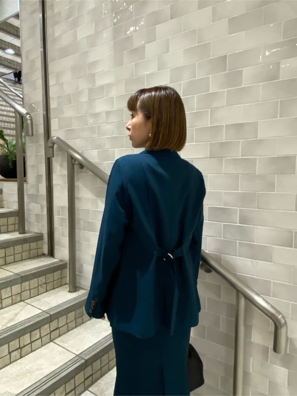 ブラック系のタンクトップ、グリーン系のテーラードジャケット、グリーン系のスカートを着用したレディースの夏コーディネートの5枚目の写真