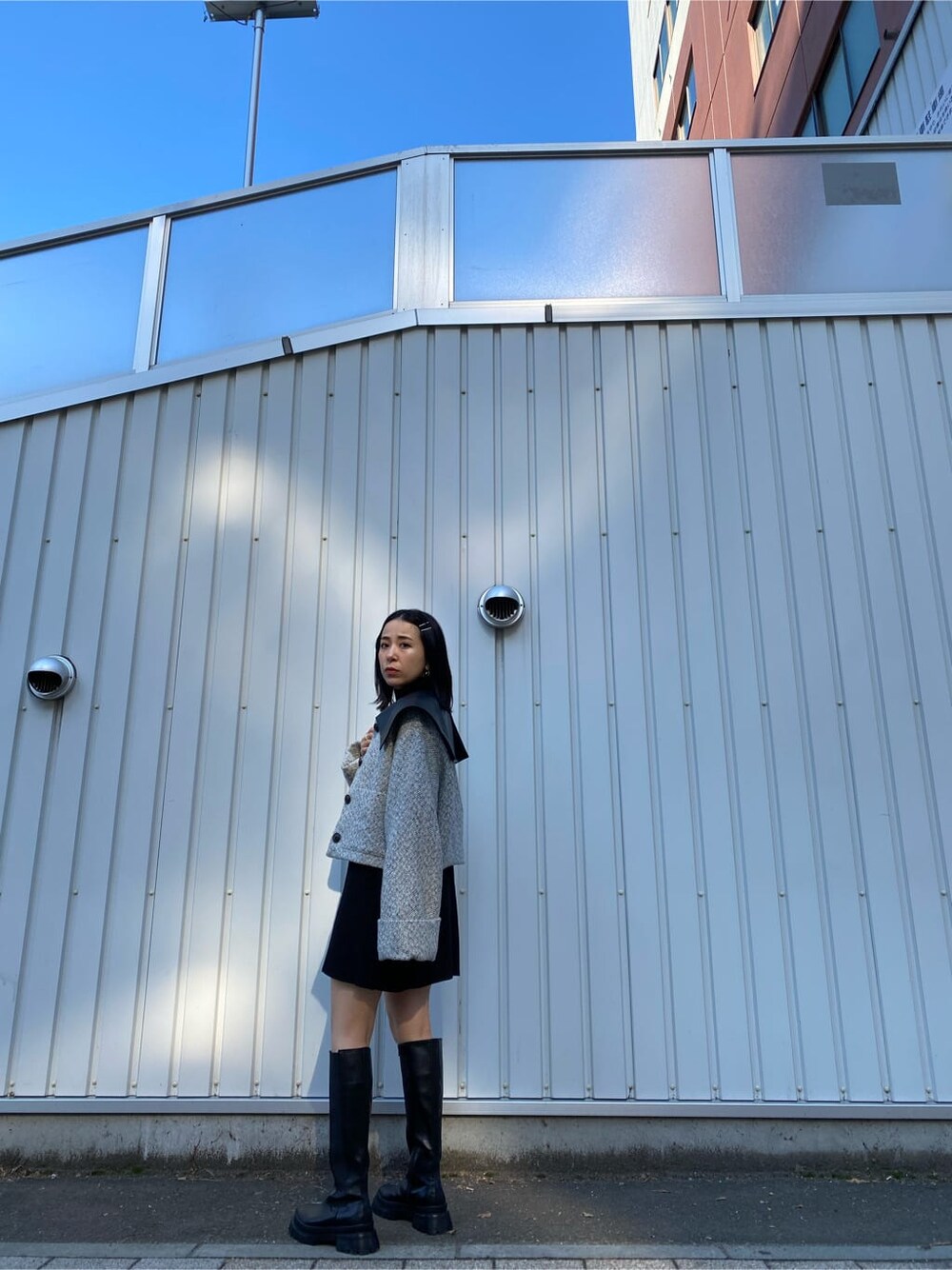 ブラック系のワンピース、ホワイト系のブルゾン、ブラック系のブーツを着用したレディースの秋コーディネートの3枚目の写真