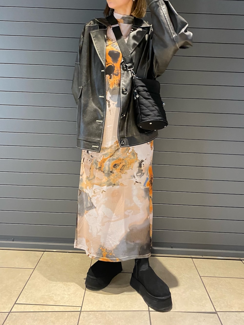 グレー系のブルゾン、オレンジ系のワンピースを着用したレディースの春コーディネートの3枚目の写真