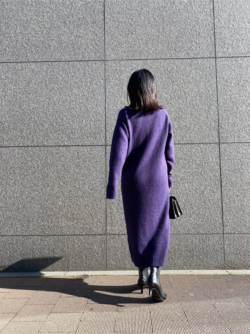 ブラック系のハンドバッグ、パープル系のワンピース、ブラック系のブーツを着用したレディースの冬コーディネートの6枚目の写真